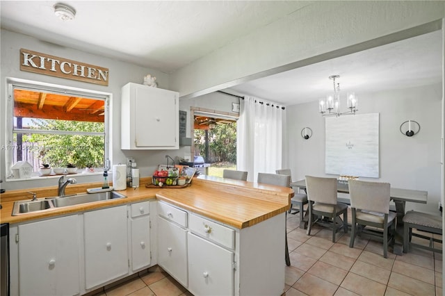 kitchen with white cabinets, light tile patterned floors, a healthy amount of sunlight, and a sink