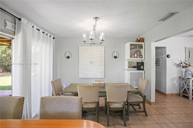 tiled dining space with a notable chandelier, visible vents, and baseboards