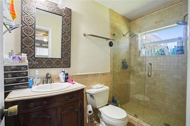 full bathroom with vanity, a stall shower, toilet, and tile walls