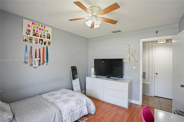 bedroom featuring baseboards, a ceiling fan, wood finished floors, and visible vents