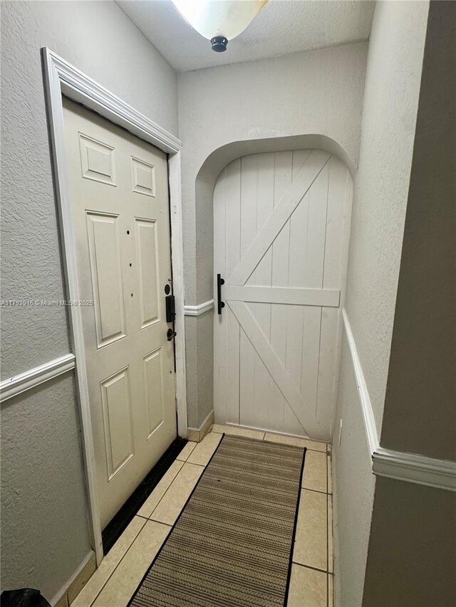 7514 NW 177th Ter Unit 7514, Hialeah, FL 33015 - doorway to outside with arched walkways, a textured wall, and light tile patterned flooring