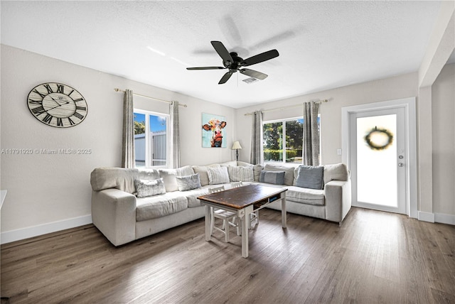 living area with a textured ceiling, baseboards, a ceiling fan, and wood finished floors
