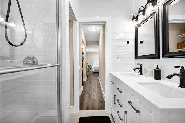 ensuite bathroom with double vanity, a sink, wood finished floors, and a shower stall