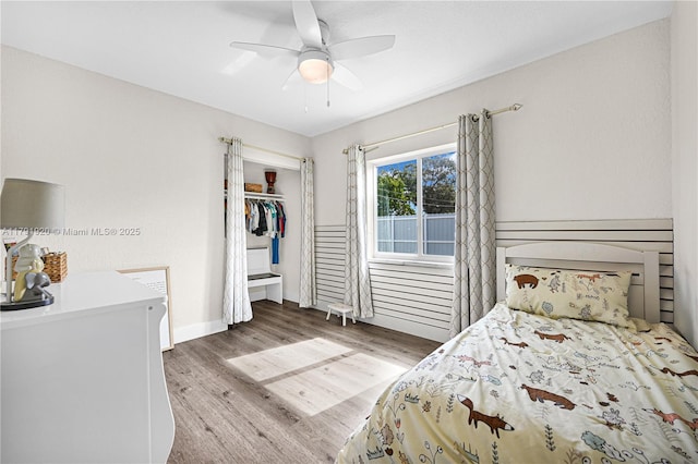 bedroom featuring a closet, baseboards, a ceiling fan, and wood finished floors