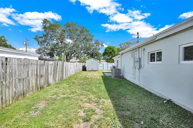 view of yard featuring a storage shed, central AC, an outdoor structure, and a fenced backyard