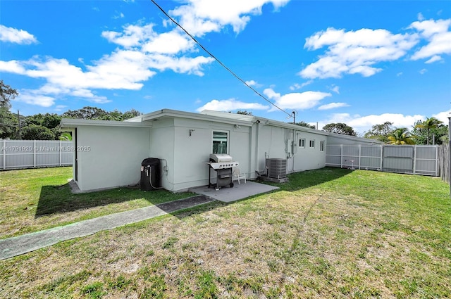 rear view of house with a yard, cooling unit, and a fenced backyard