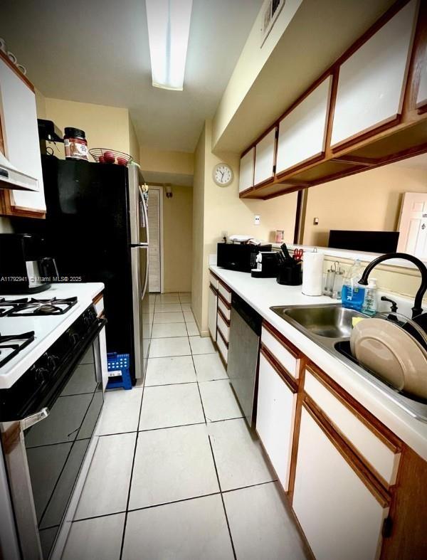 kitchen featuring visible vents, dishwasher, a sink, light countertops, and range with gas stovetop