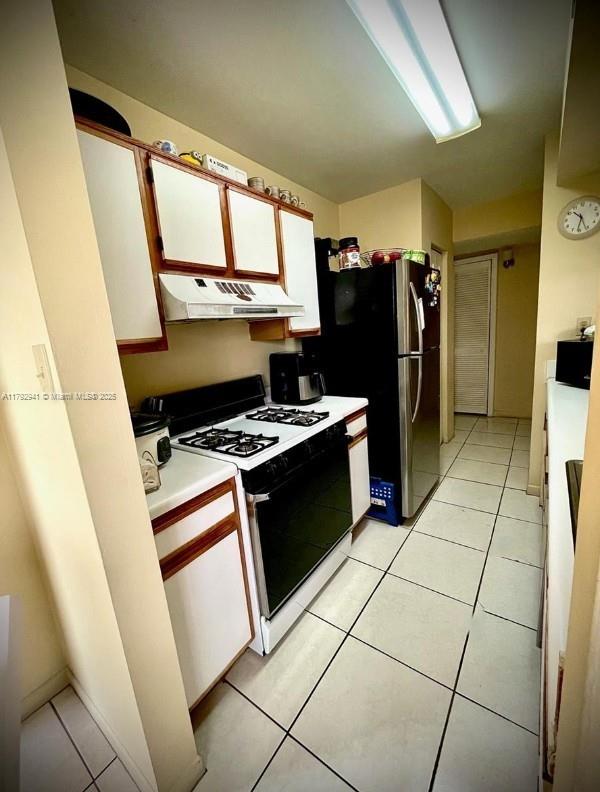 15320 SW 106th Ter Unit 1108, Miami, FL 33196 - kitchen featuring under cabinet range hood, range with gas cooktop, white cabinetry, freestanding refrigerator, and light countertops