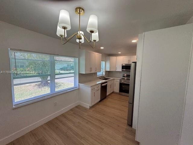 13333 SW 112th Pl, Miami, FL 33176 - kitchen featuring light countertops, white cabinetry, a sink, light wood-style flooring, and appliances with stainless steel finishes