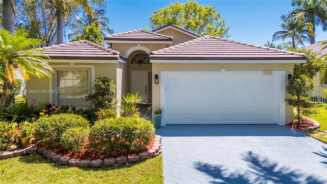 mediterranean / spanish-style house featuring a garage, a tiled roof, driveway, and stucco siding