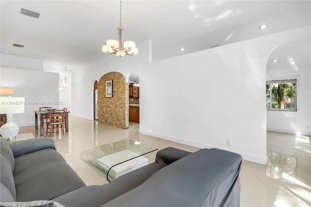 living room with visible vents, arched walkways, light tile patterned floors, and a chandelier