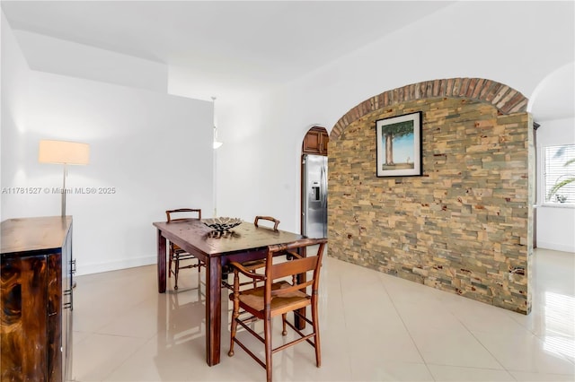 dining room featuring arched walkways and light tile patterned flooring