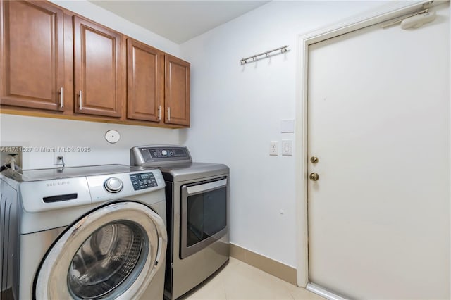 washroom featuring baseboards, washing machine and dryer, cabinet space, and light tile patterned flooring