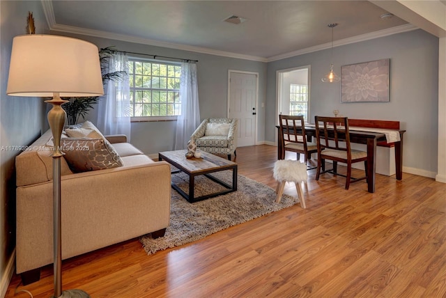 living room with visible vents, baseboards, wood finished floors, and a wealth of natural light