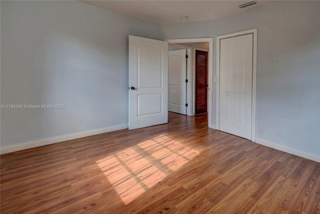 empty room featuring visible vents, baseboards, and wood finished floors