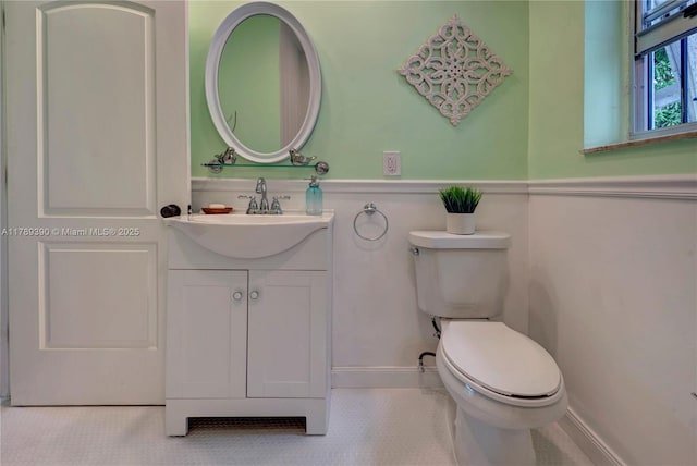 half bath featuring vanity, baseboards, and toilet