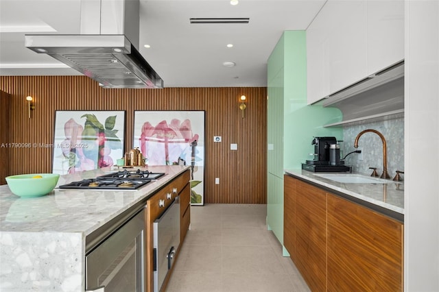 3737 Collins Ave Unit S-1303, Miami Beach, FL 33140 - kitchen with a sink, stainless steel gas cooktop, modern cabinets, white cabinets, and wall chimney exhaust hood
