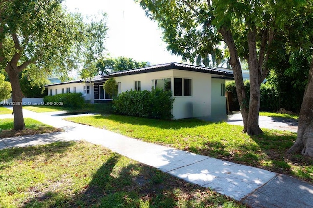 ranch-style home featuring stucco siding and a front yard
