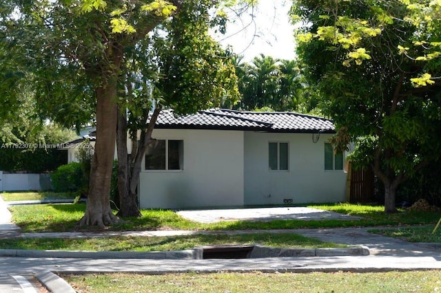 view of side of property featuring stucco siding, a tile roof, and fence