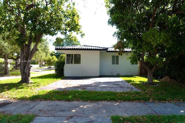 view of property exterior with a yard, stucco siding, a patio, and a tiled roof