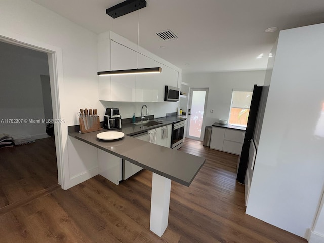 kitchen featuring dark countertops, visible vents, stainless steel microwave, and a sink