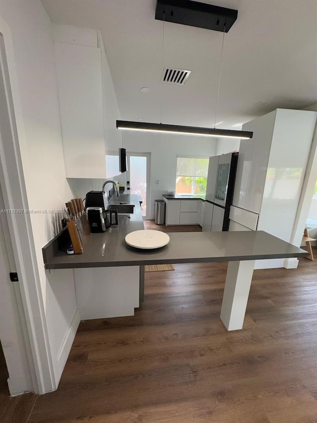 kitchen with dark countertops, a sink, visible vents, and dark wood-style floors