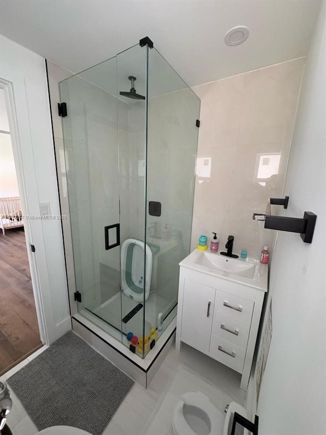 bathroom with vanity, toilet, tile walls, and a stall shower