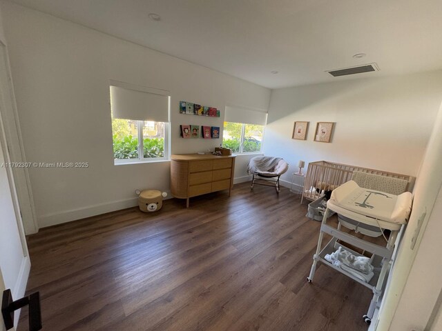 bedroom with baseboards, visible vents, and wood finished floors