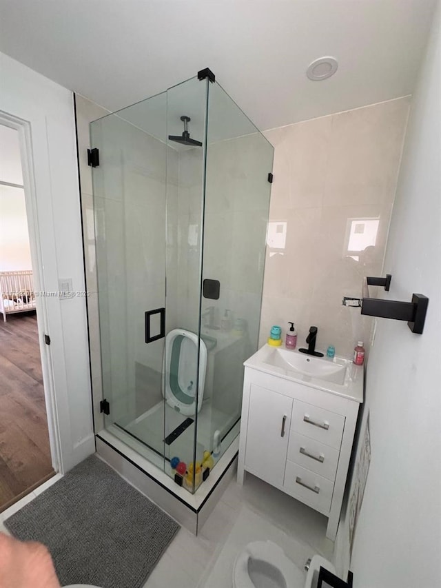bathroom featuring a stall shower, tile walls, and vanity