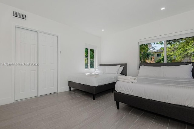 bedroom with multiple windows, recessed lighting, visible vents, and wood finished floors