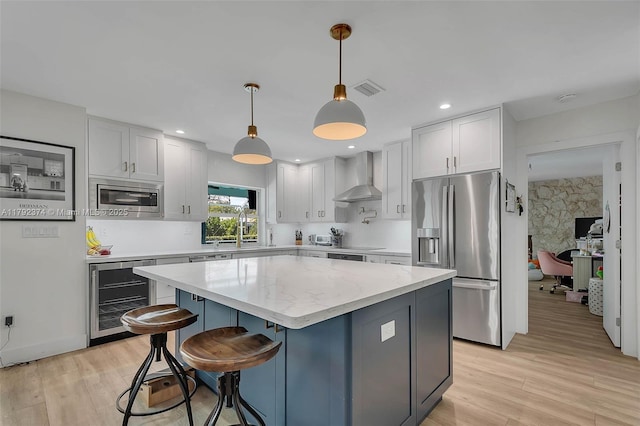 16840 SW 87th Ave, Palmetto Bay, FL 33157 - kitchen featuring wine cooler, stainless steel appliances, wall chimney exhaust hood, a kitchen island, and light wood-style flooring