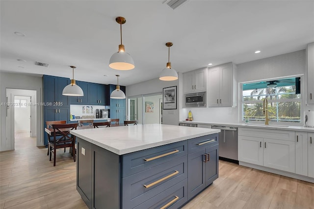 16840 SW 87th Ave, Palmetto Bay, FL 33157 - kitchen with appliances with stainless steel finishes, light wood-style flooring, a center island, decorative light fixtures, and light stone countertops