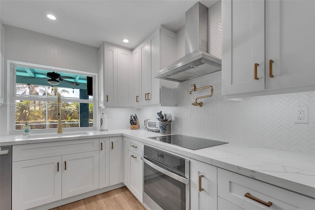 16840 SW 87th Ave, Palmetto Bay, FL 33157 - kitchen featuring wall chimney exhaust hood, appliances with stainless steel finishes, white cabinets, decorative backsplash, and light wood-type flooring