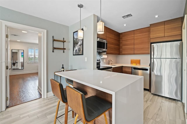 1770 E Las Olas Blvd Unit 507, Fort Lauderdale, FL 33301 - kitchen featuring stainless steel appliances, brown cabinets, light countertops, modern cabinets, and decorative light fixtures