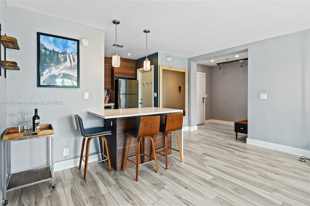 1770 E Las Olas Blvd Unit 507, Fort Lauderdale, FL 33301 - kitchen with freestanding refrigerator, baseboards, light countertops, a kitchen breakfast bar, and light wood-style flooring