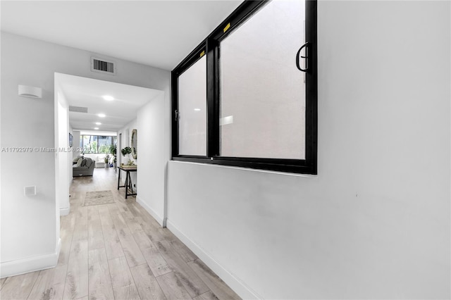 hallway featuring baseboards, wood finished floors, and visible vents