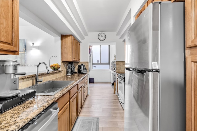 kitchen with a sink, decorative backsplash, stainless steel appliances, and light wood-style flooring