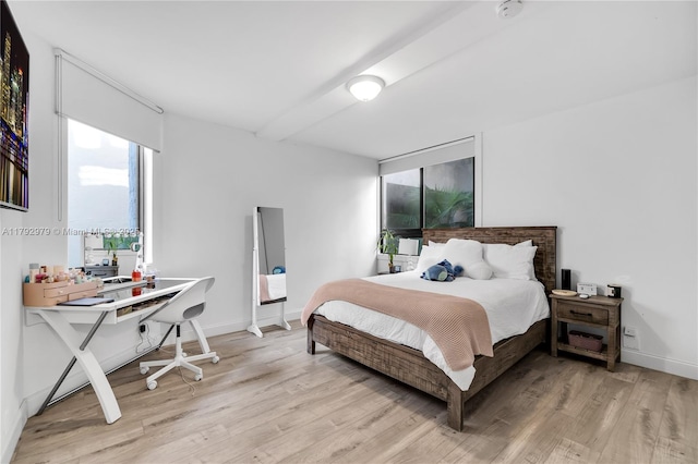 bedroom featuring baseboards, light wood-style flooring, and beam ceiling