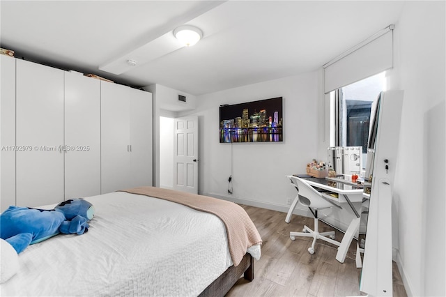 bedroom featuring a closet, baseboards, visible vents, and light wood-type flooring