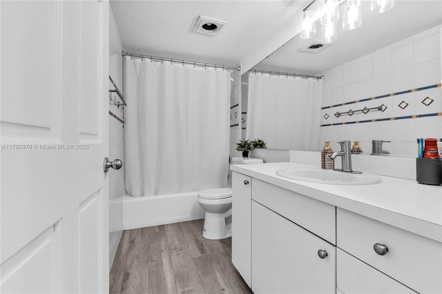 bathroom featuring vanity, shower / bath combo with shower curtain, toilet, and wood finished floors