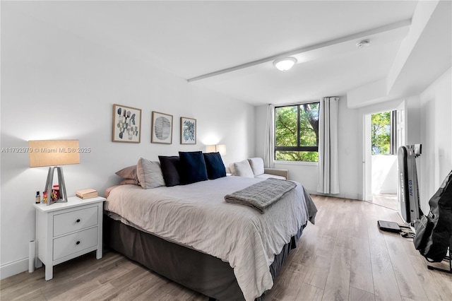 bedroom featuring baseboards, light wood-style flooring, and access to exterior