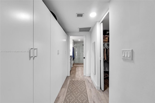 hallway featuring visible vents, baseboards, and light wood-type flooring