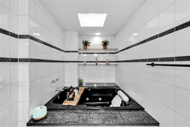 interior space featuring a skylight, dark countertops, tile walls, black cooktop, and white cabinetry