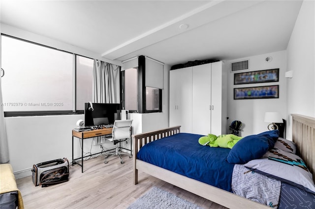 bedroom with a closet, wood finished floors, and visible vents