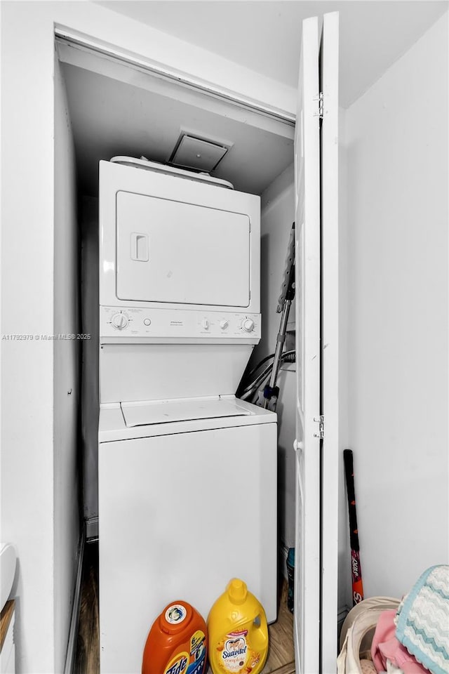 clothes washing area with laundry area, wood finished floors, and stacked washer / dryer