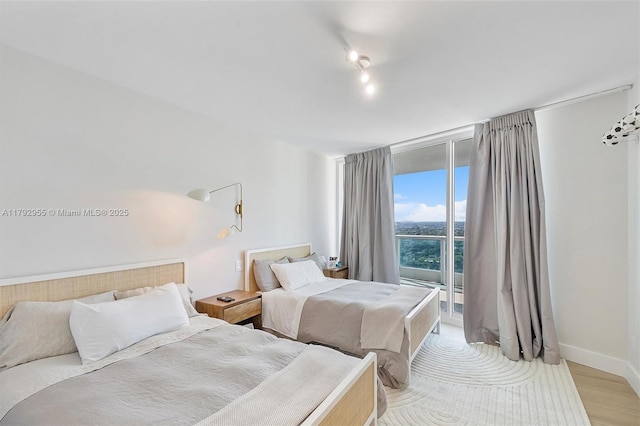 2127 Brickell Ave Unit 2704, Miami, FL 33129 - bedroom with access to outside, baseboards, expansive windows, and light wood-type flooring