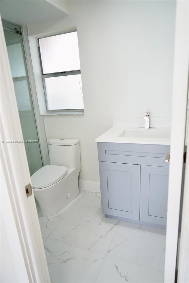 bathroom featuring vanity, marble finish floor, baseboards, and toilet