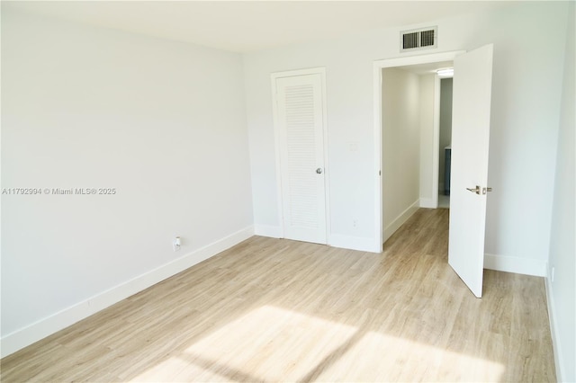 unfurnished bedroom featuring baseboards, a closet, light wood-type flooring, and visible vents