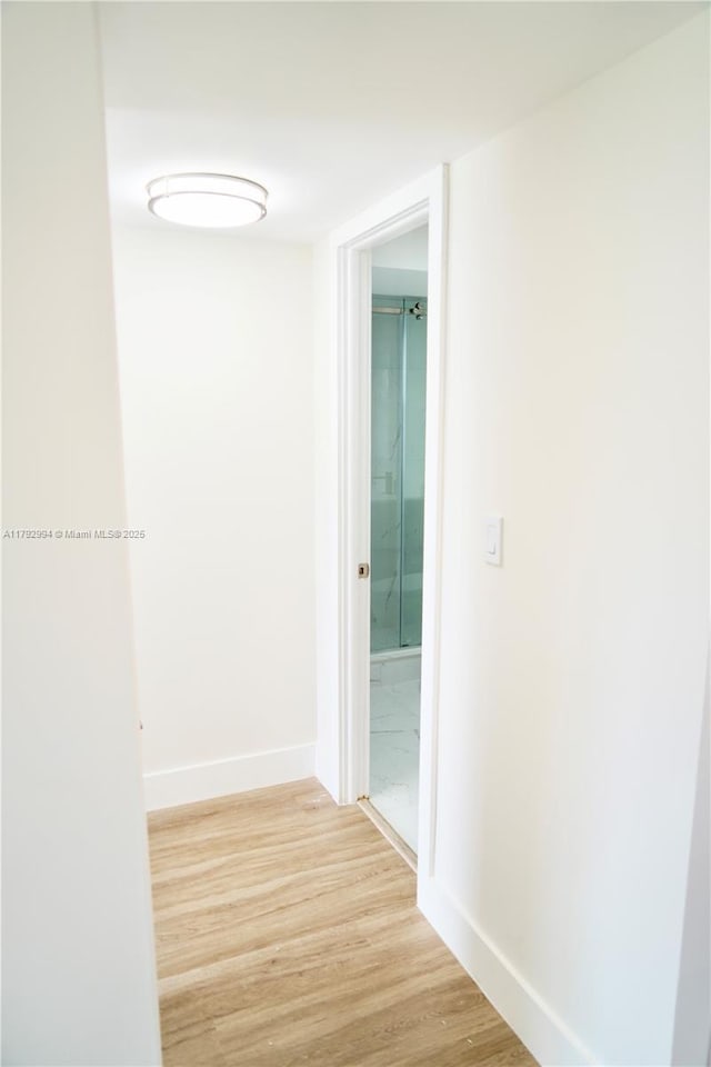 hall with light wood-style floors and baseboards