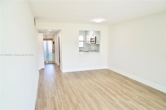 unfurnished living room featuring baseboards and light wood-style floors